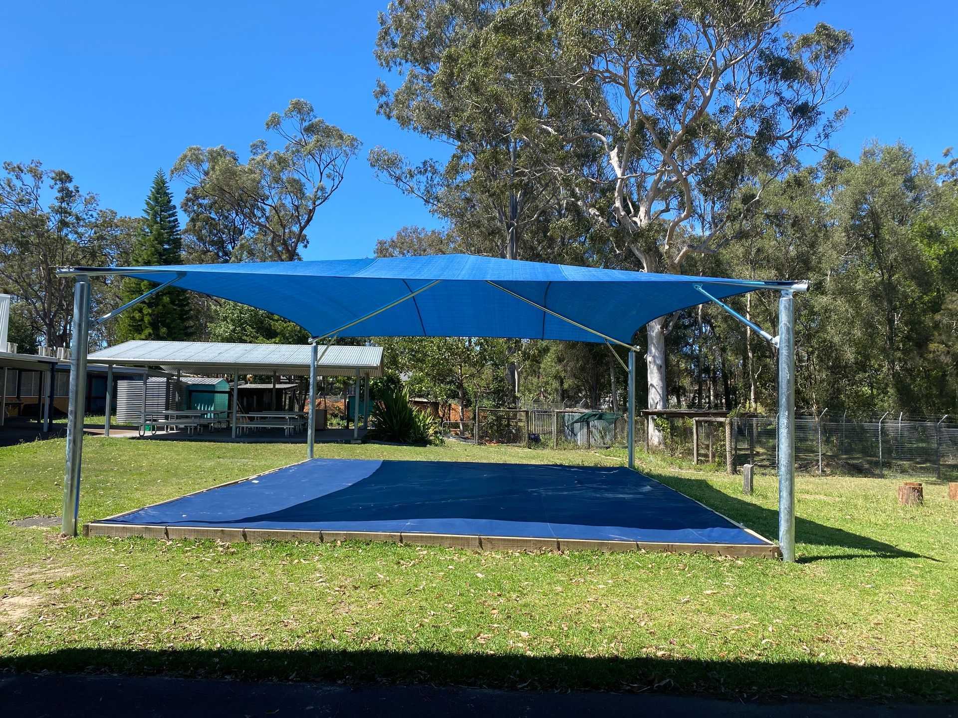 A blue shade canopy covers a rectangular area on a grassy lawn with trees in the background under a clear blue sky — Shades of Blue In North Wyong, NSW
