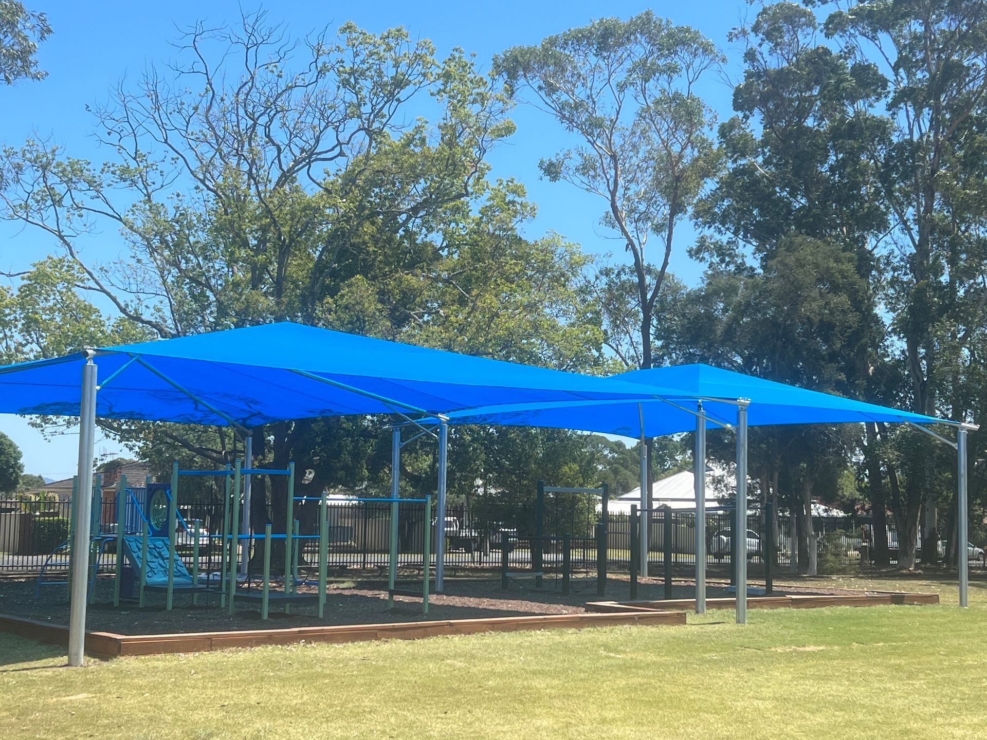 A blue sun shade structure covers a playground on a sunny day with trees in the background — Shades of Blue In North Wyong, NSW