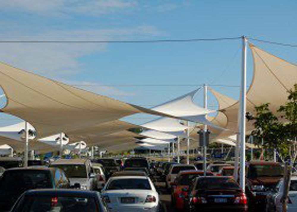 A parking lot covered by large, beige triangular shade sails, with many parked cars visible underneath — Shades of Blue In North Wyong, NSW