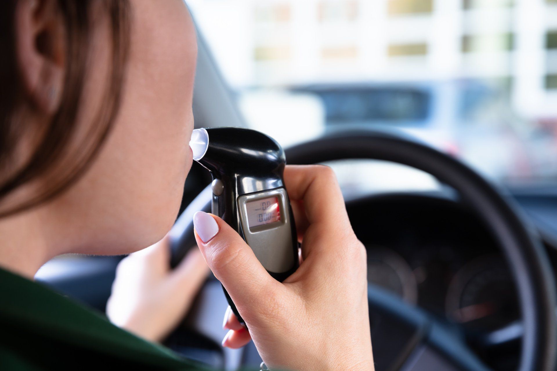 Female blowing into a breathalyzer in the car