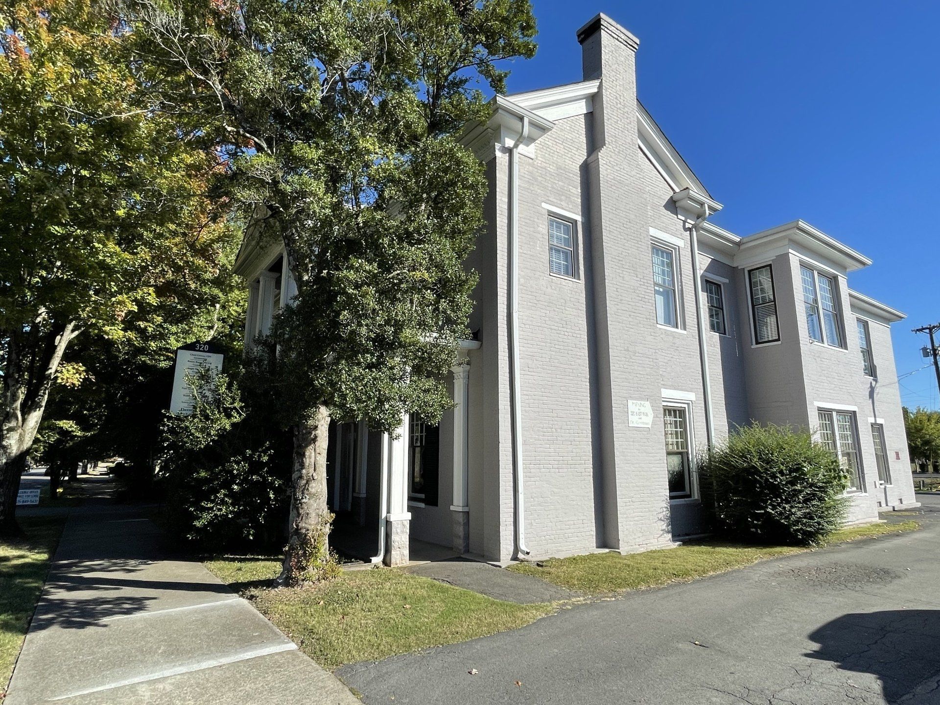 A large white house with a lot of windows and trees in front of it.
