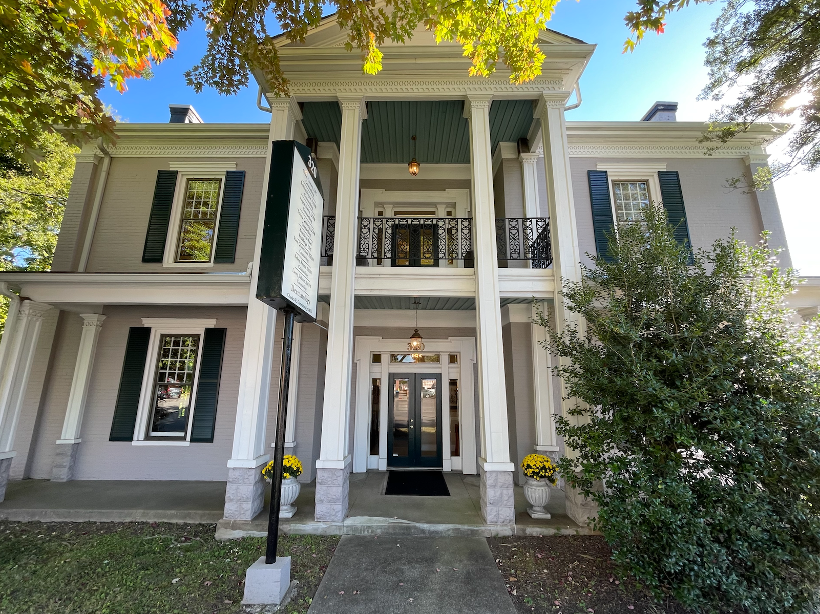 A large white house with black shutters and a sign that says ' a ' on it