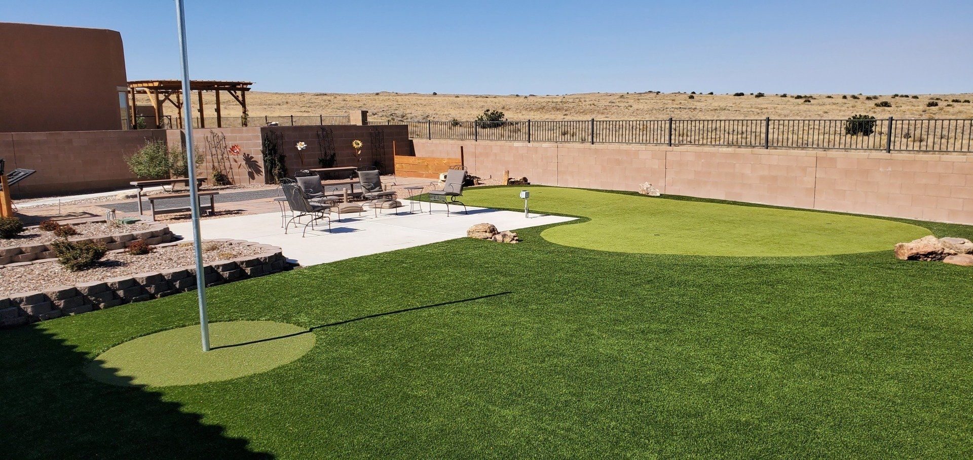 A backyard with a putting green and a flag pole