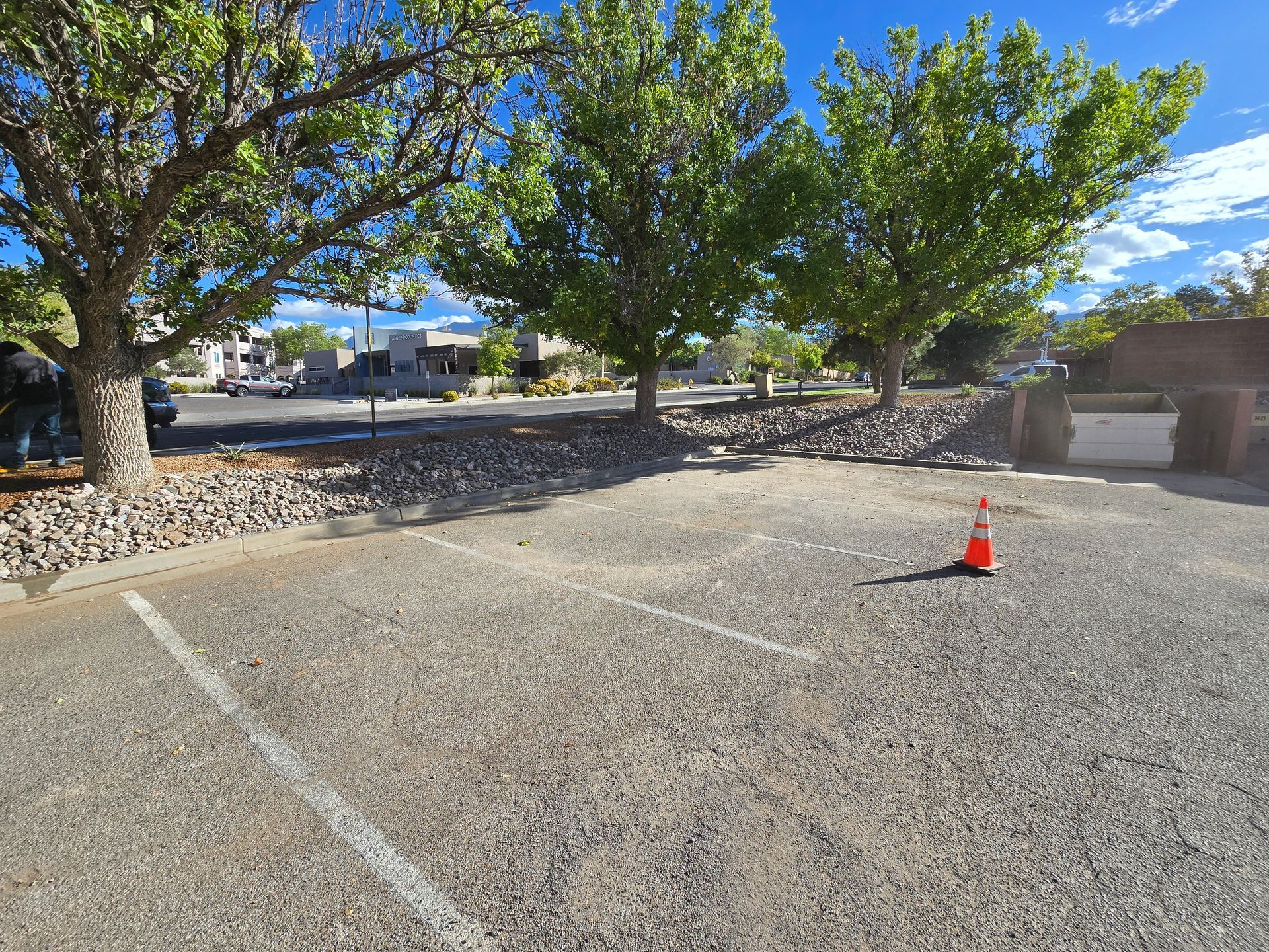 A parking lot with trees and a cone in the middle