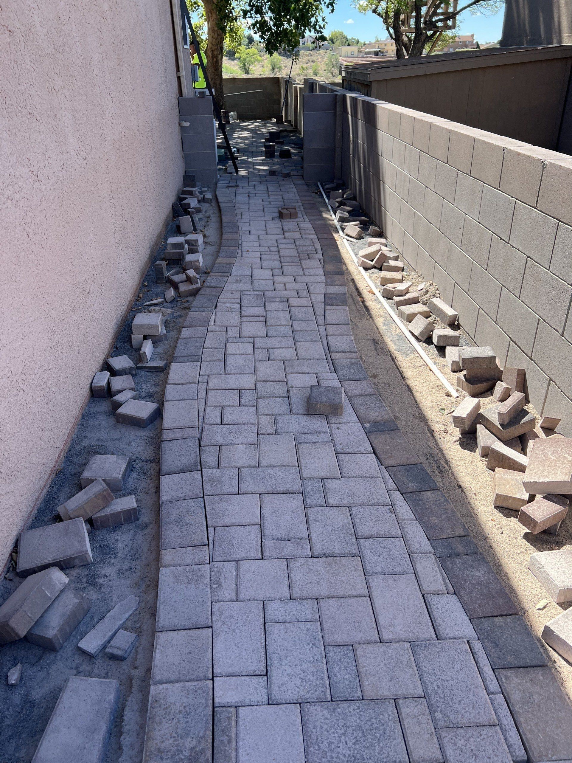 A brick walkway is being built next to a brick wall.