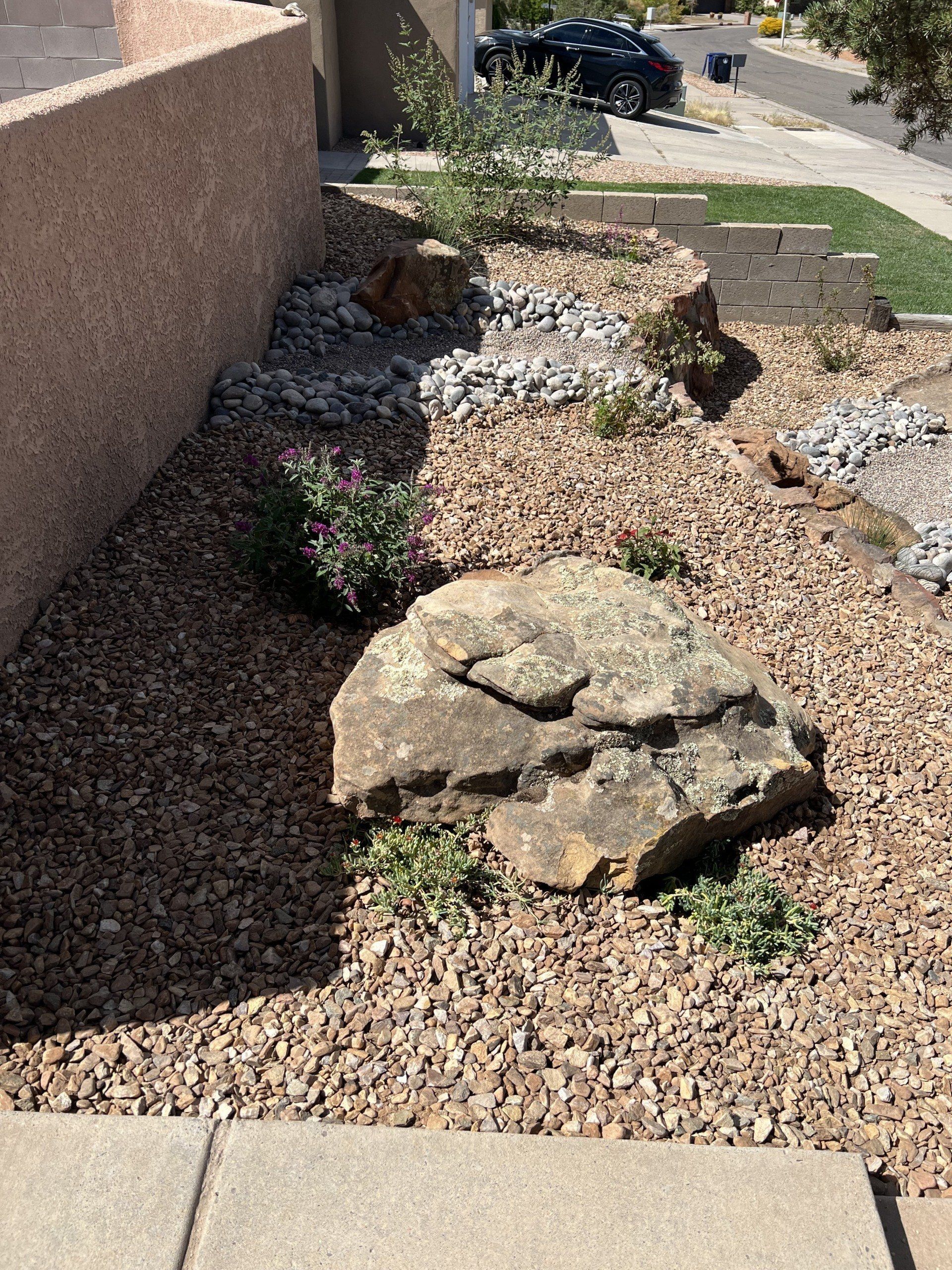 A large rock is sitting in the middle of a gravel garden.