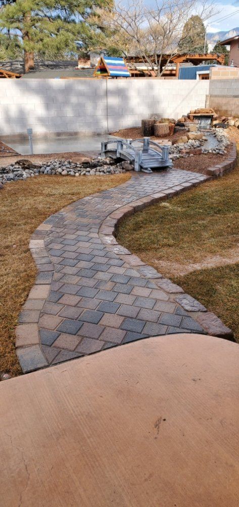 A brick walkway leading to a pool in a backyard.