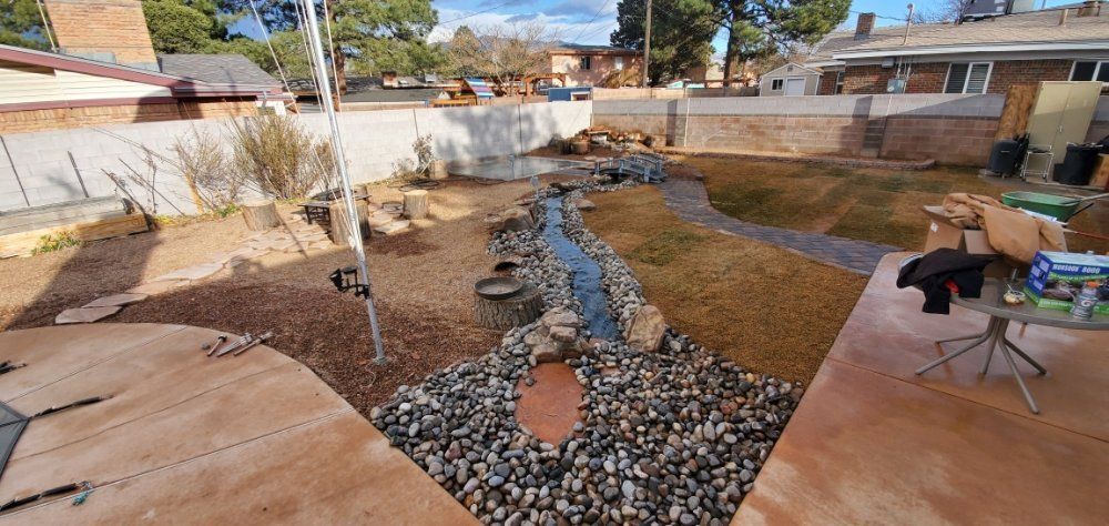 A backyard with a stream running through it and a table in the foreground.