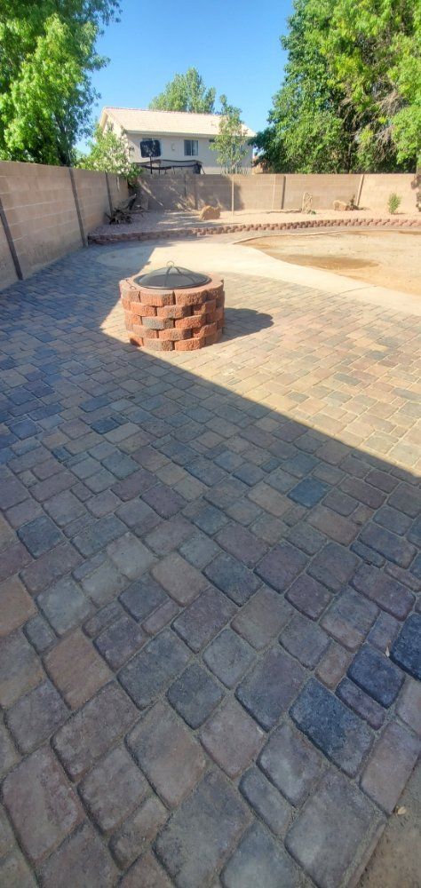 A brick patio with a fire pit in the middle of it.