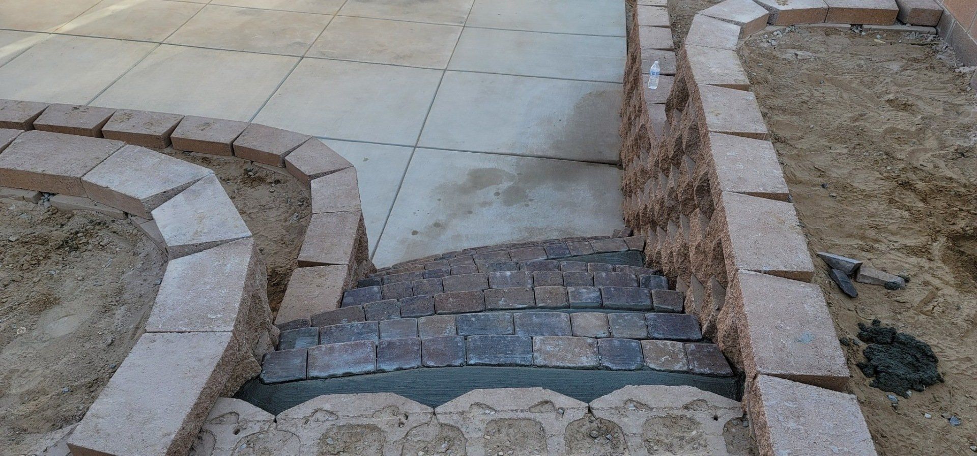 A brick walkway is being built next to a concrete walkway.