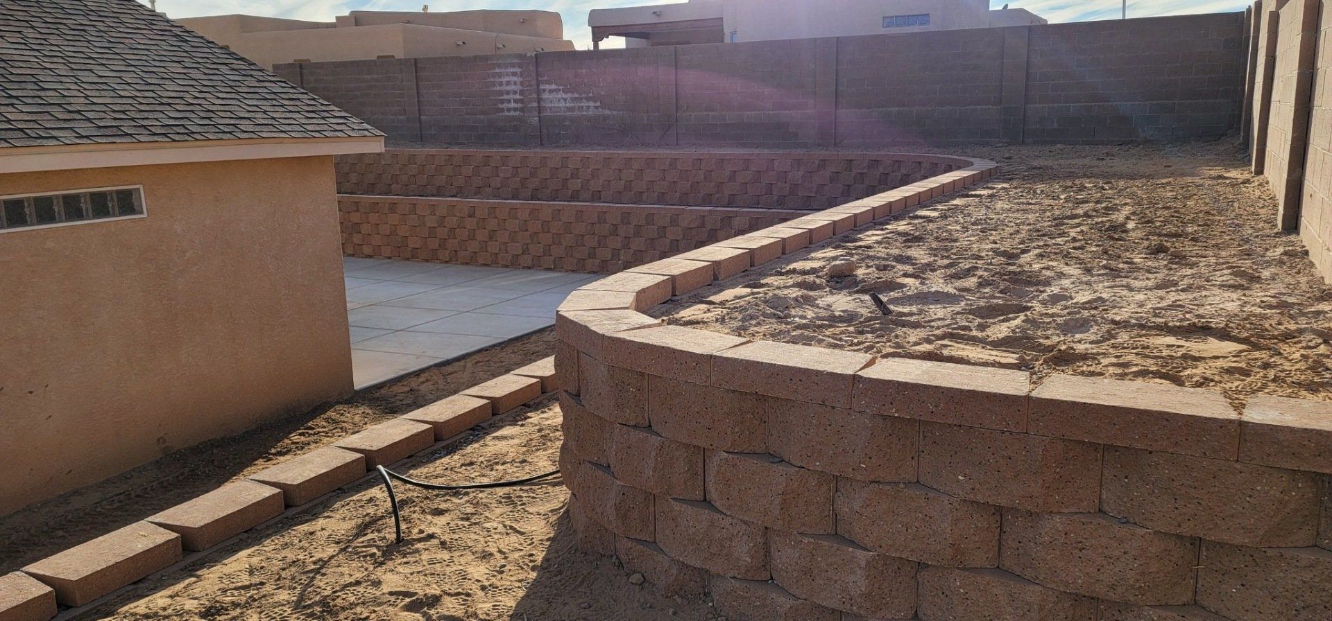A brick wall is being built in the backyard of a house.