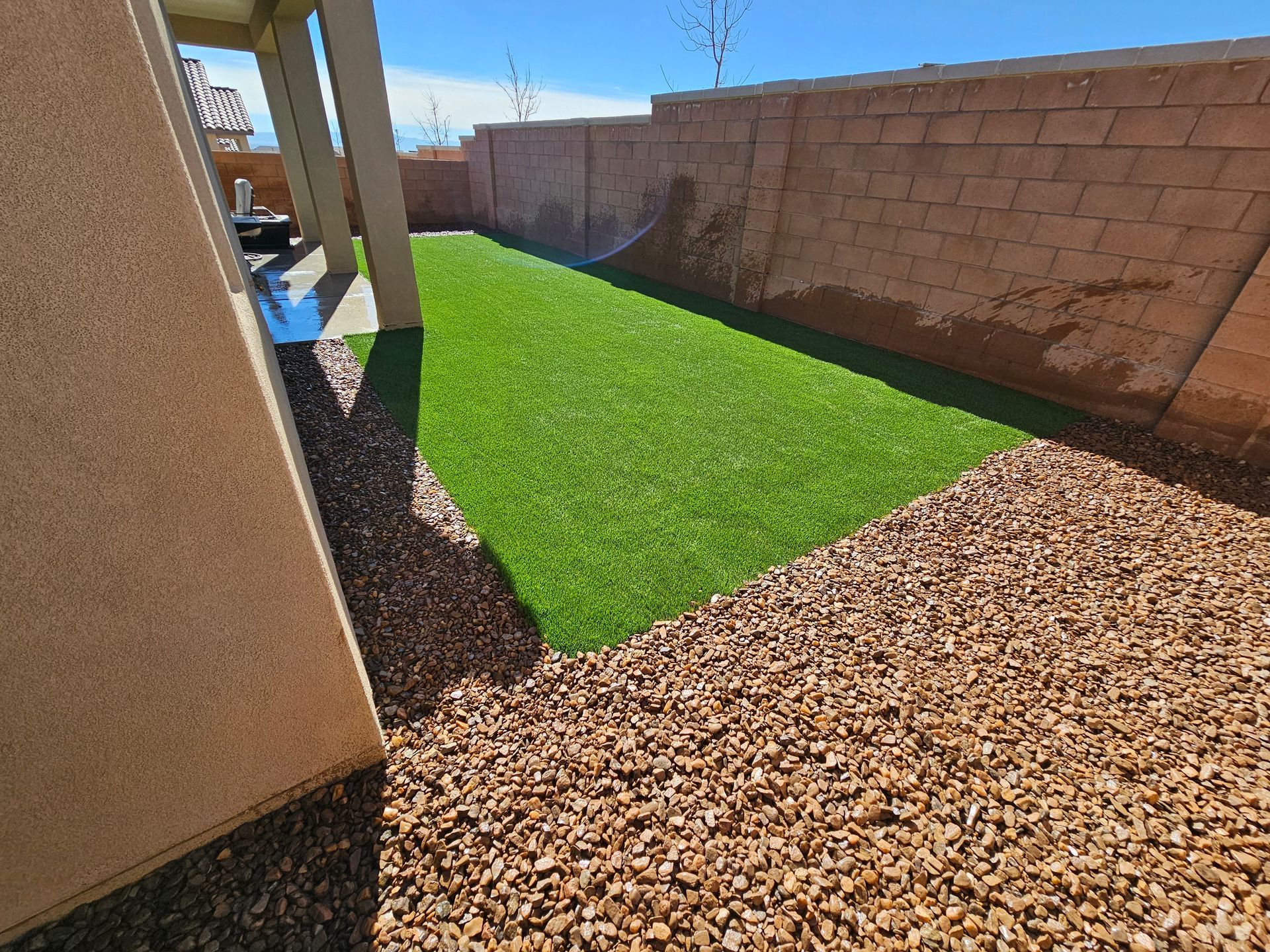 A backyard with a brick wall and a lush green lawn.