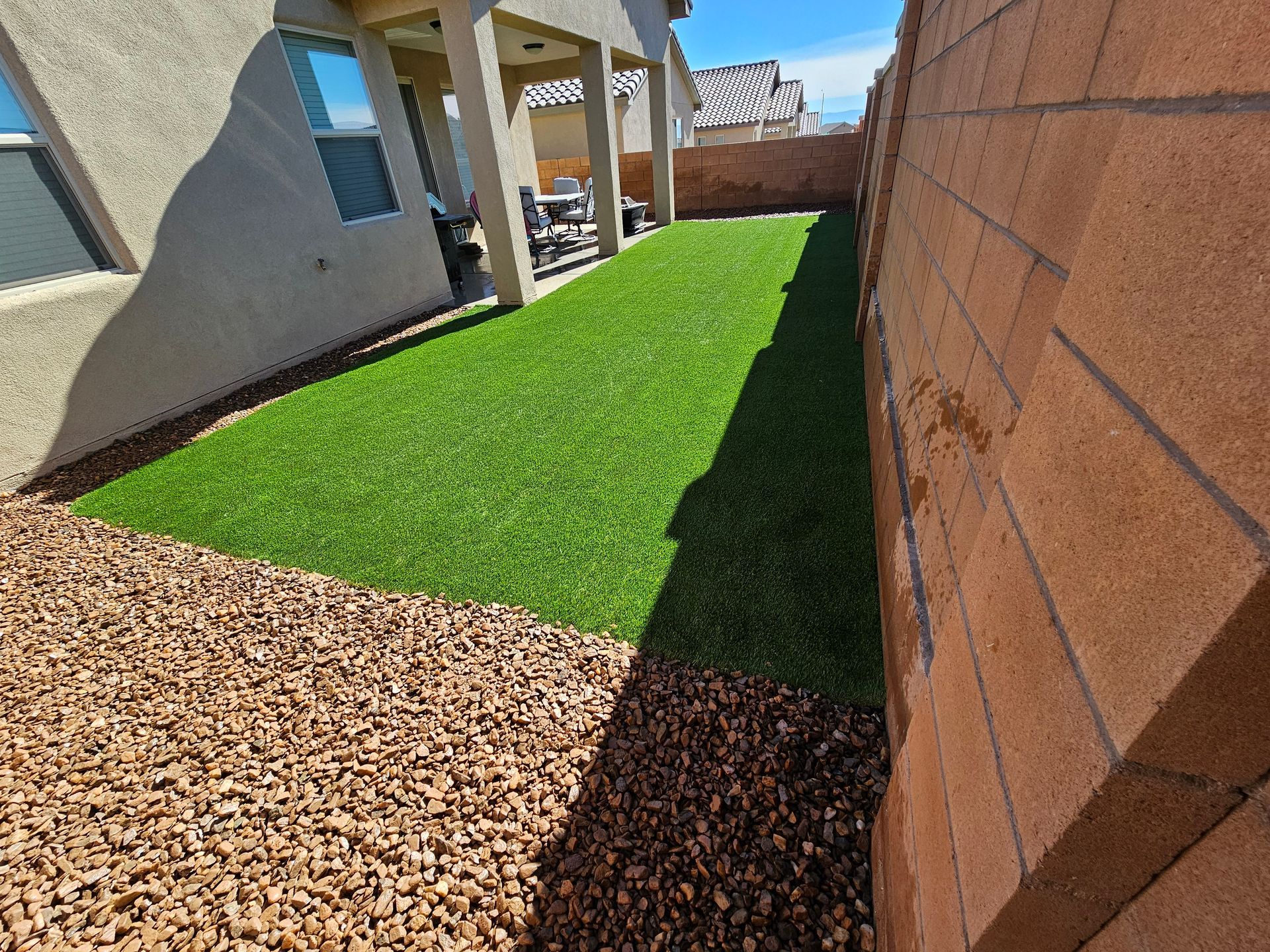 A backyard with a brick wall and a lush green lawn.
