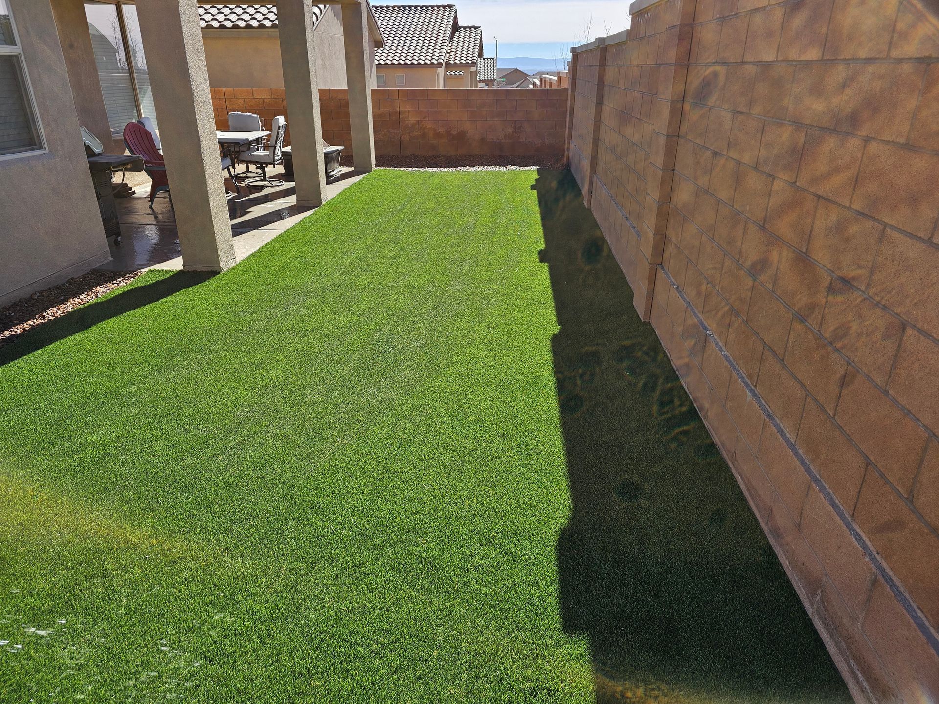 A backyard with a fence and a lush green lawn.