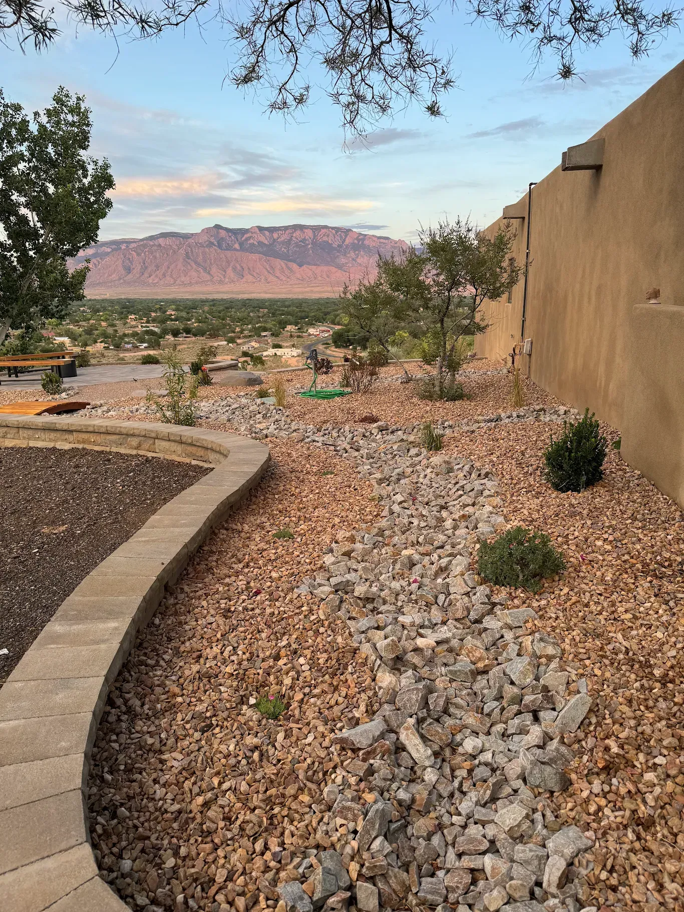 A stone walkway leading to a house with a mountain in the background.