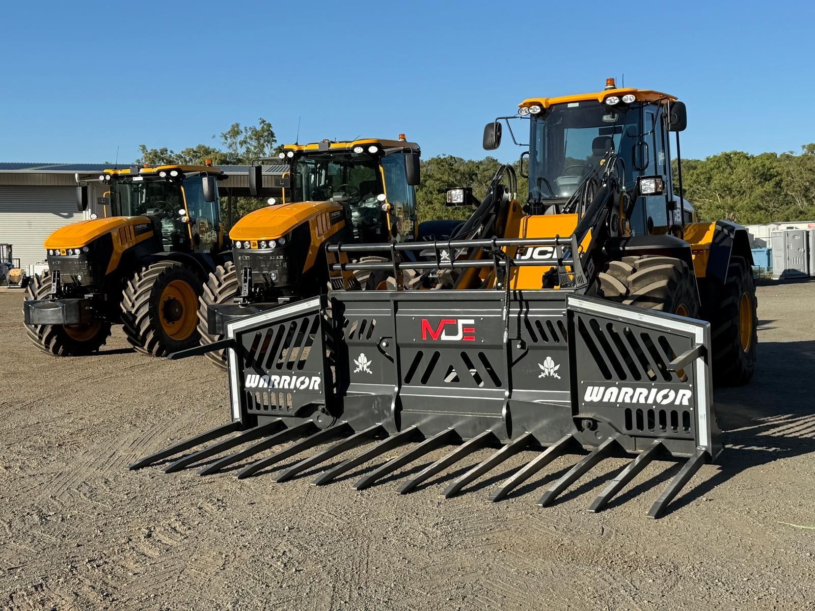 Three yellow JCB agricultural tractors parked on a gravel lot, the front one equipped with a large black 