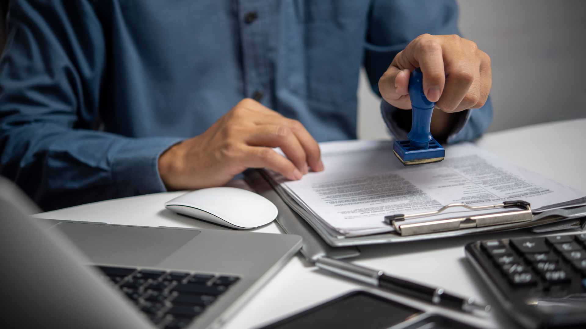 A man is stamping a document on a clipboard.