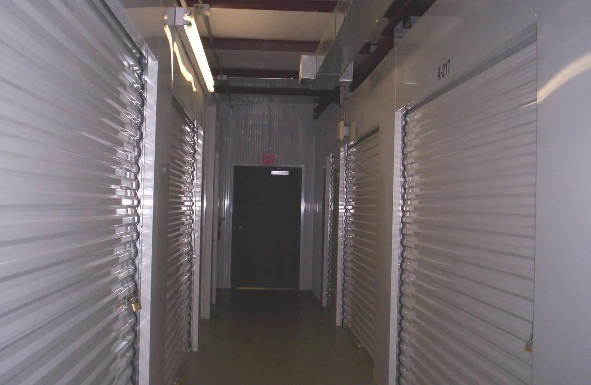 A hallway with a red exit sign on the door