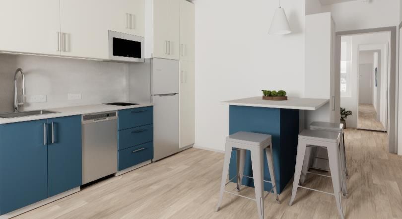 A kitchen with blue cabinets , stools , a table and a refrigerator.