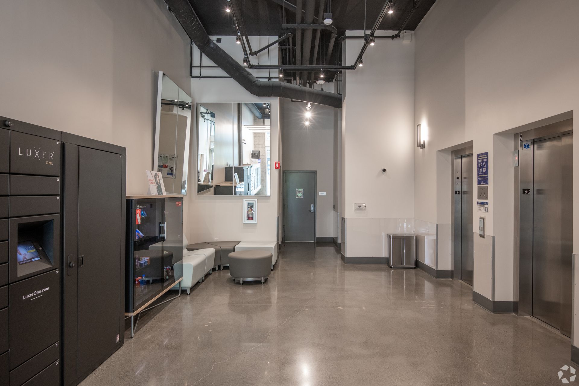 A large lobby with elevators and lockers in a building.