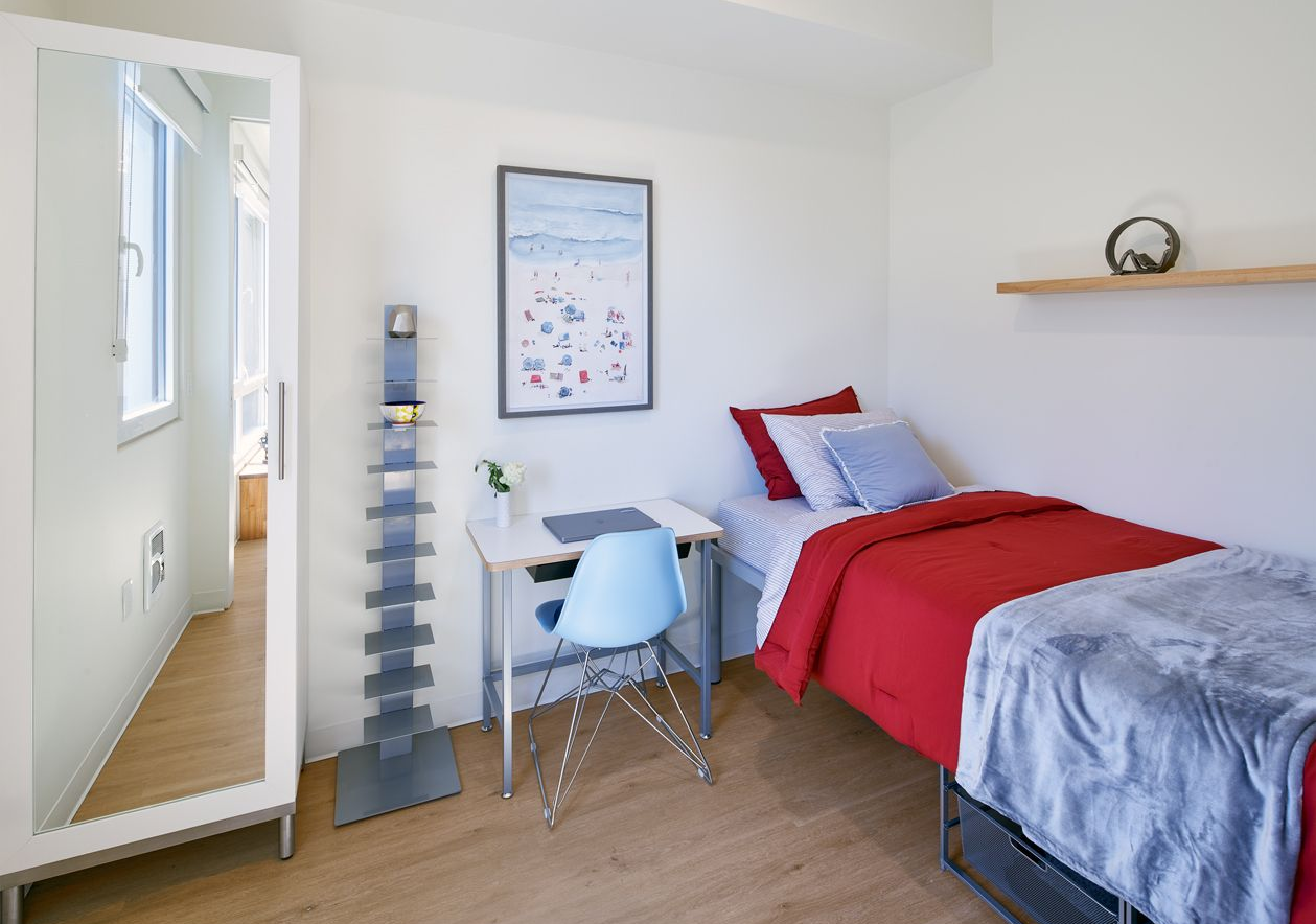 A bedroom with a bed , wardrobe , mirror and window.