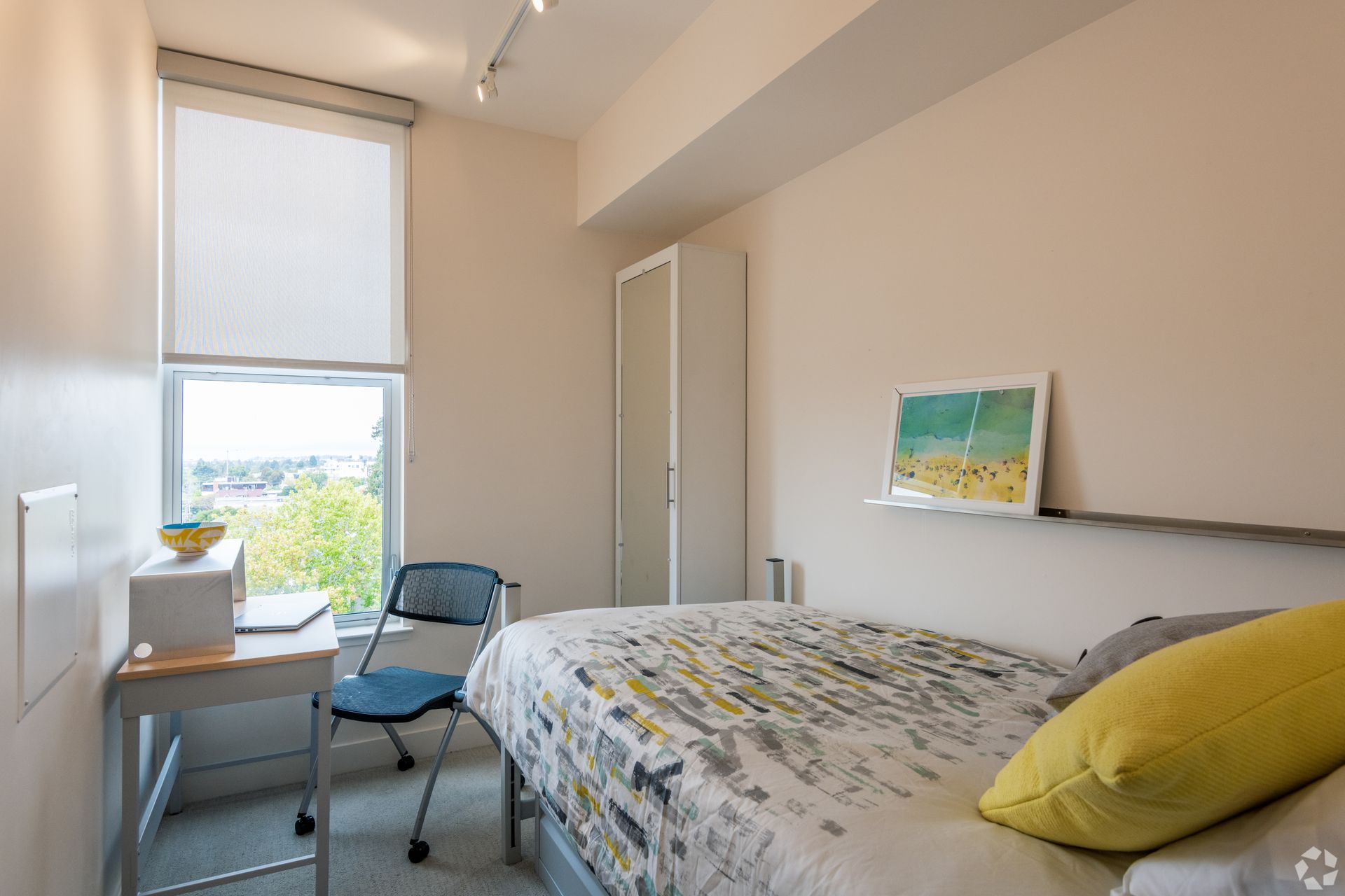 A bedroom with a bed , desk , chair and window.
