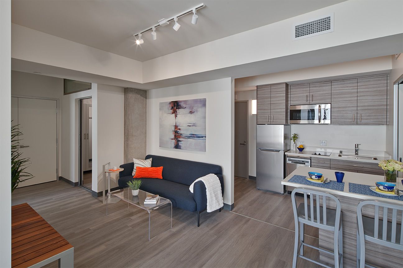 A living room with a couch , table , chairs and a kitchen.