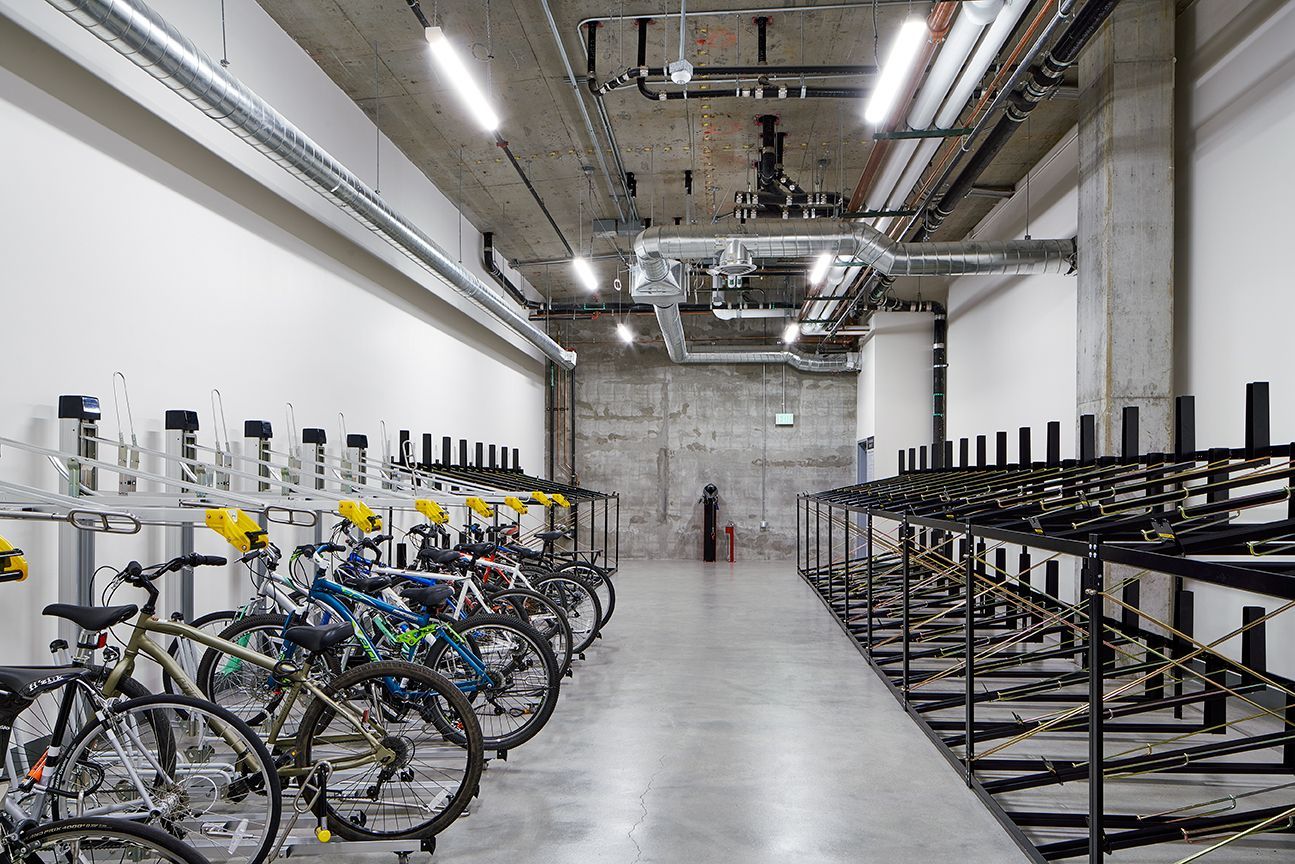 A row of bicycles are parked in a warehouse.