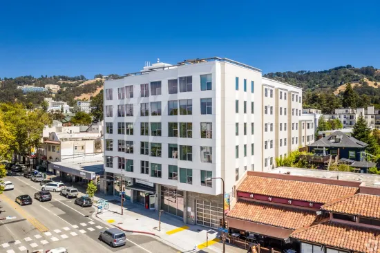 A large white building is sitting on the corner of a city street.