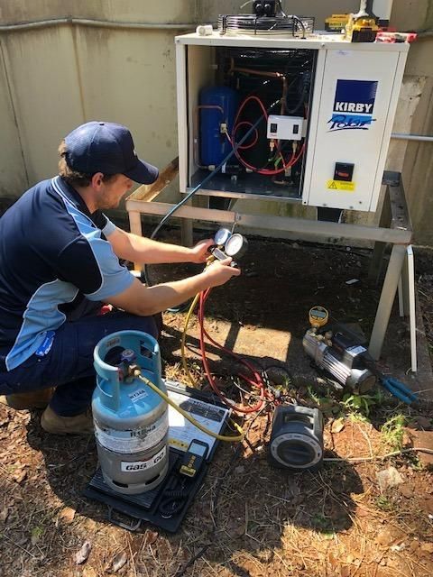 A Man Is Working on An Air Conditioner Outside of A Building — Northernair in East Lismore, NSW