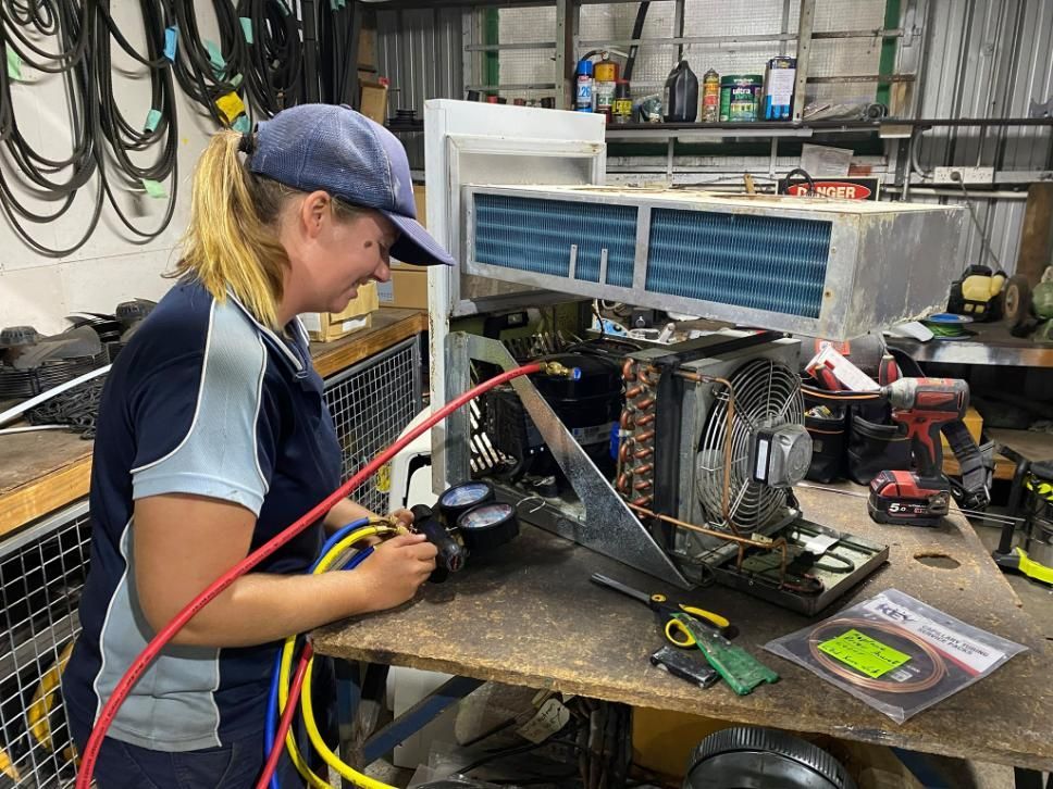 A Woman Is Working on An Air Conditioner in A Garage — Northernair in East Lismore, NSW