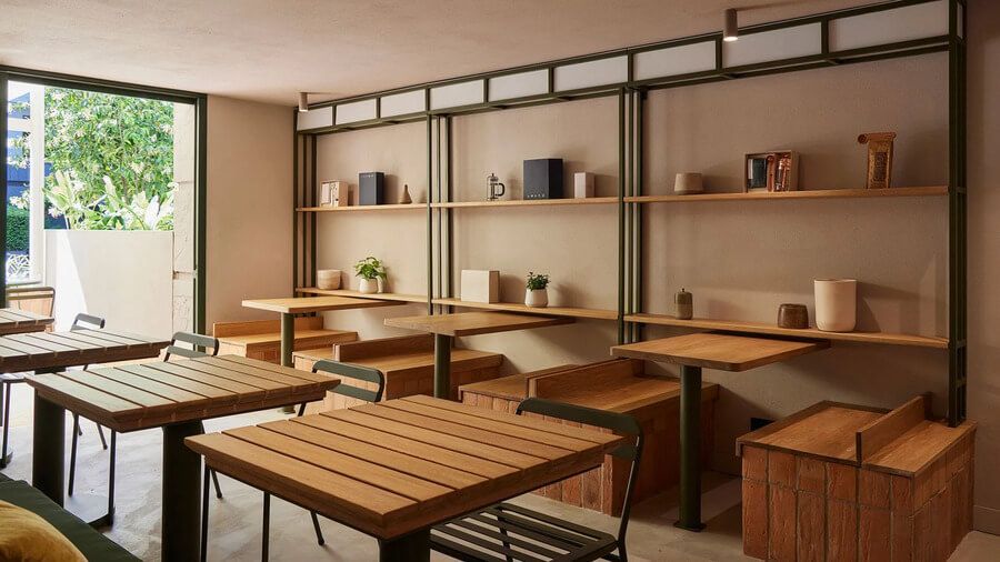 Comedor interior con mesas de madera y estanterías decorativas en un ambiente luminoso