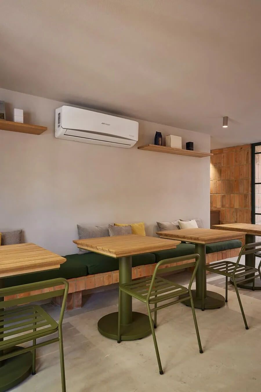 Área de comedor interior con mesas de madera, sillas verdes y decoración minimalista