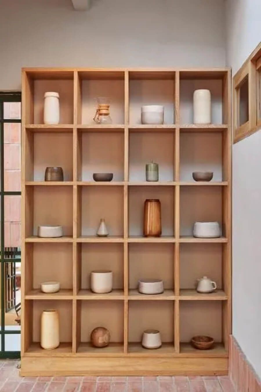 Estantería de madera con decoraciones minimalistas en un ambiente luminoso