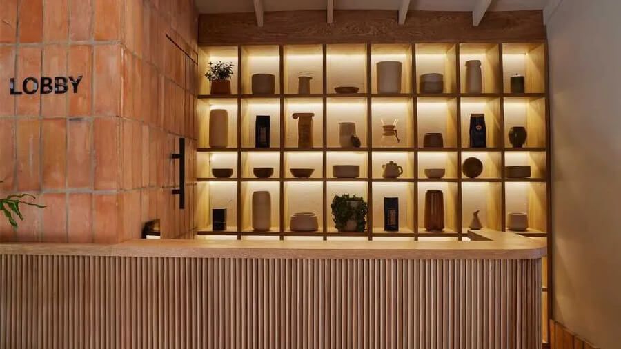 Mostrador de recepción con estantería iluminada y decoración minimalista en el lobby del hotel