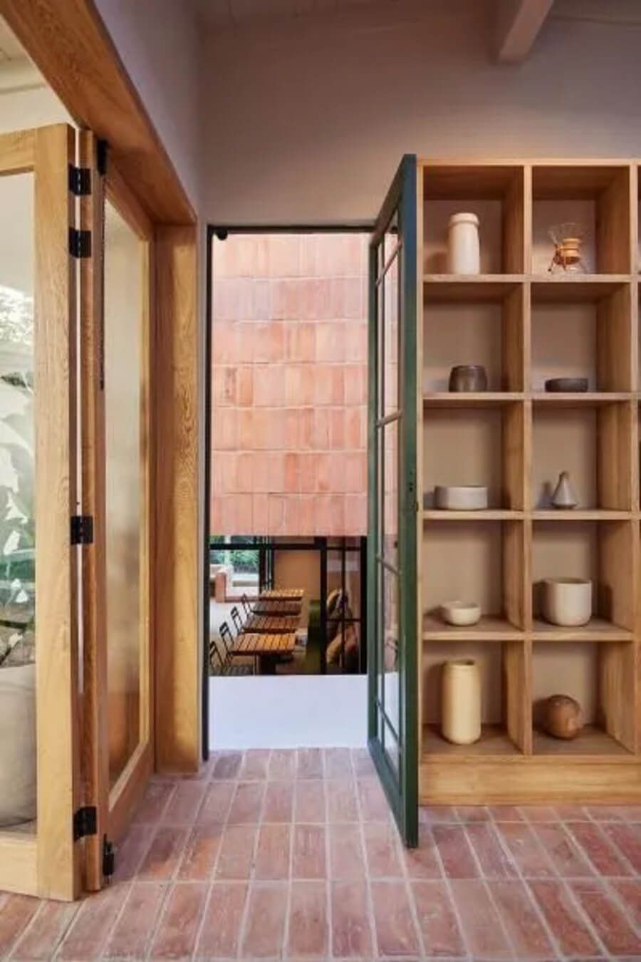 Pasillo con puertas abiertas y estantería decorativa en un ambiente minimalista