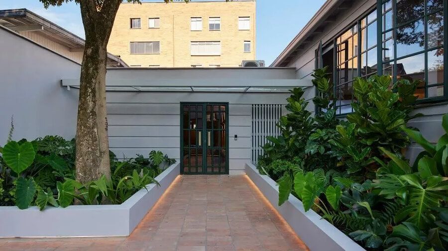 Entrada moderna del hotel con jardín y camino de ladrillo rodeado de plantas