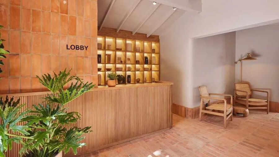 Recepción de hotel con diseño cálido de ladrillo y madera, junto a un rincón de descanso