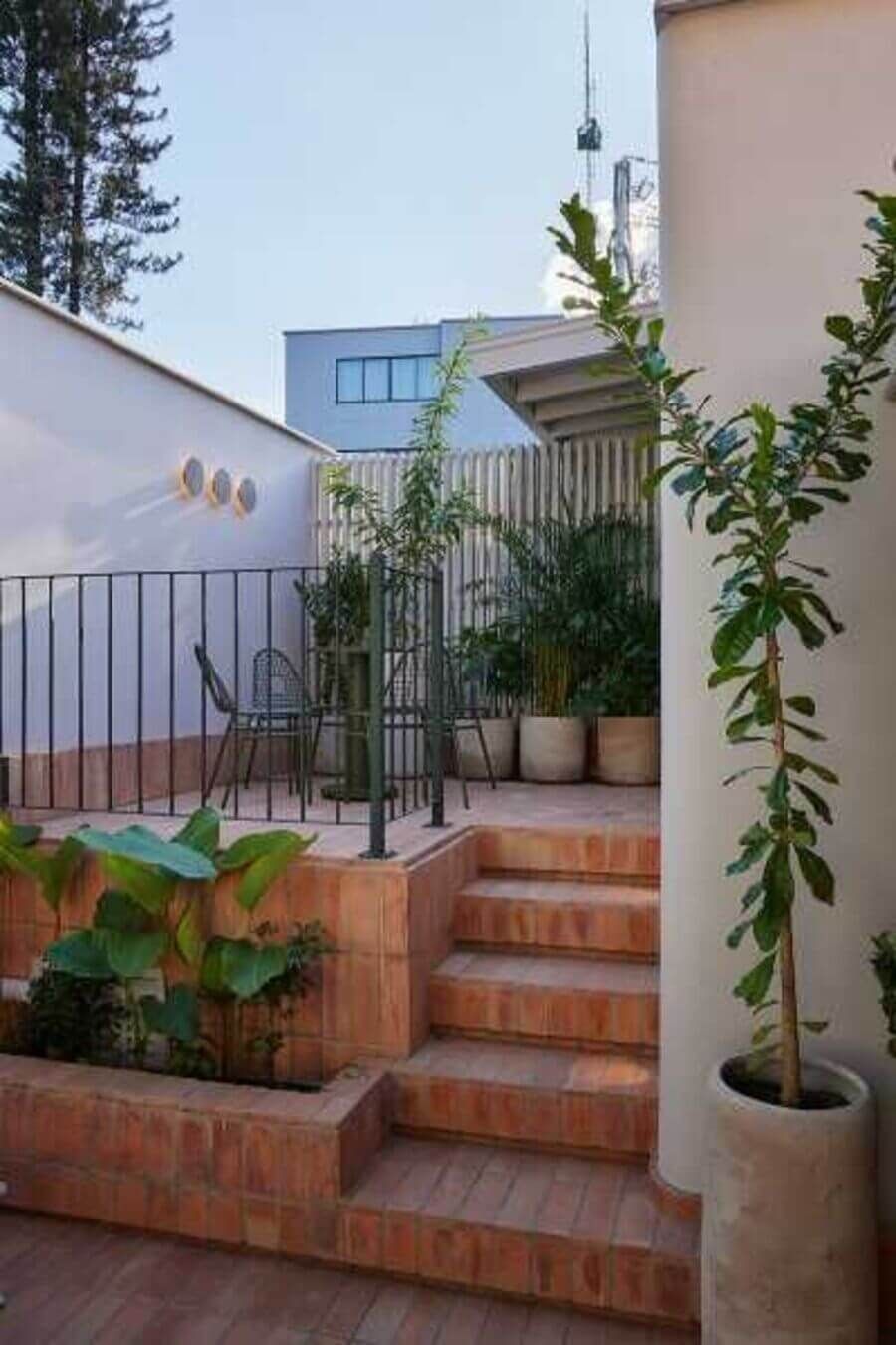 Escaleras de ladrillo que conducen a una terraza con macetas y plantas en un ambiente tranquilo