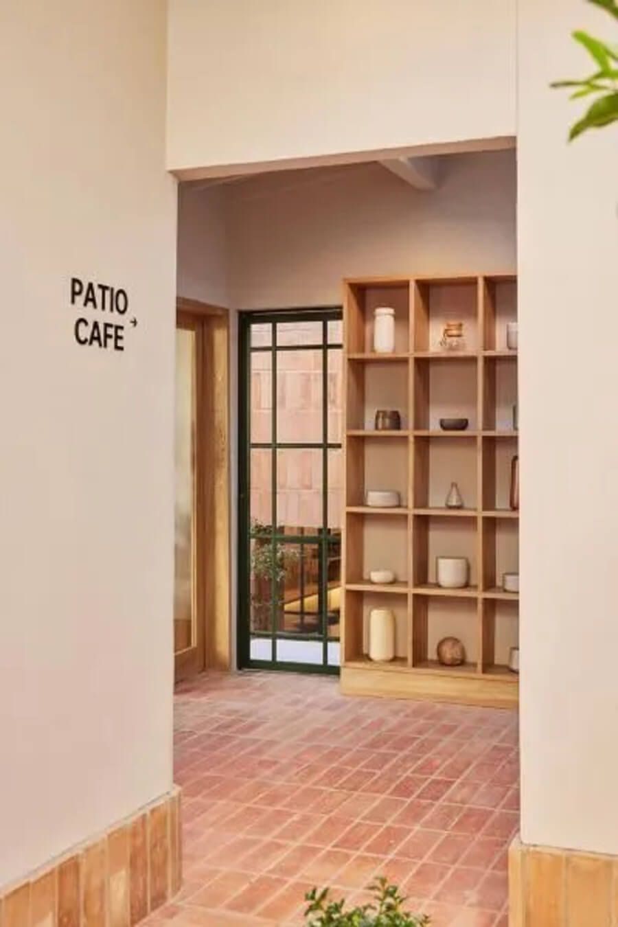 Pasillo que conduce al Patio Café con estantería de madera y decoración minimalista