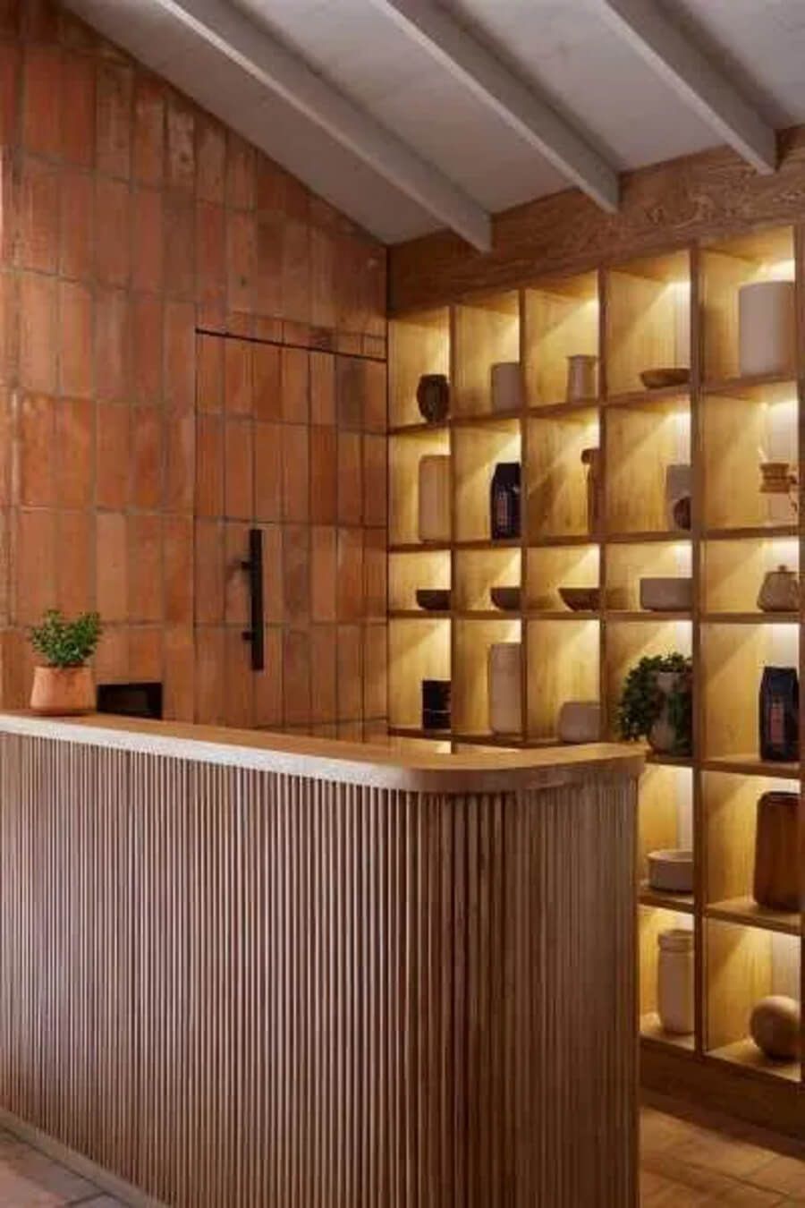 Mostrador de recepción en hotel con estantería iluminada y paredes de ladrillo