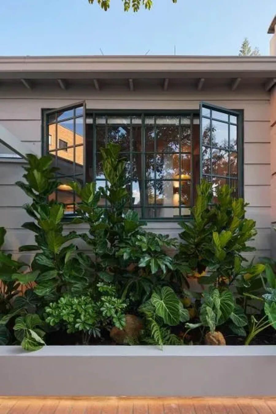 Ventana abierta con vista a un jardín frondoso en el exterior del hotel