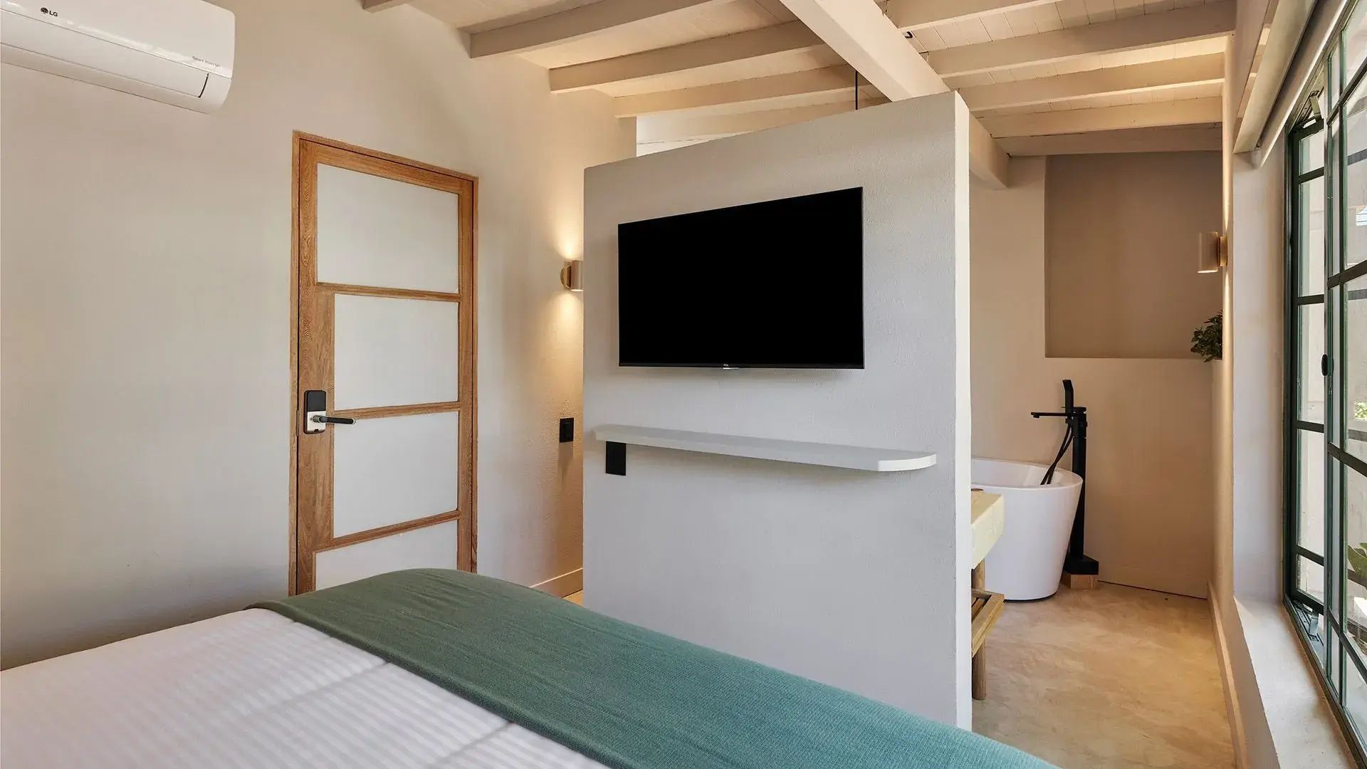 Habitación de suite superior Flores en Antípoda Hotel Boutique Medellín, equipada con una moderna televisión de pantalla plana y decoración minimalista para una estancia de lujo.