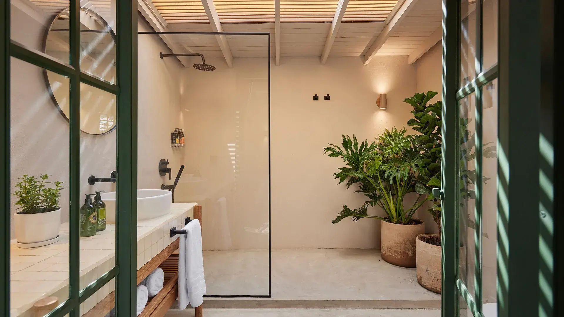 Baño de las habitaciones de suite superior Lombok en el Antípoda Hotel Boutique Medellín, con diseño moderno, plantas decorativas y una ducha de vidrio.