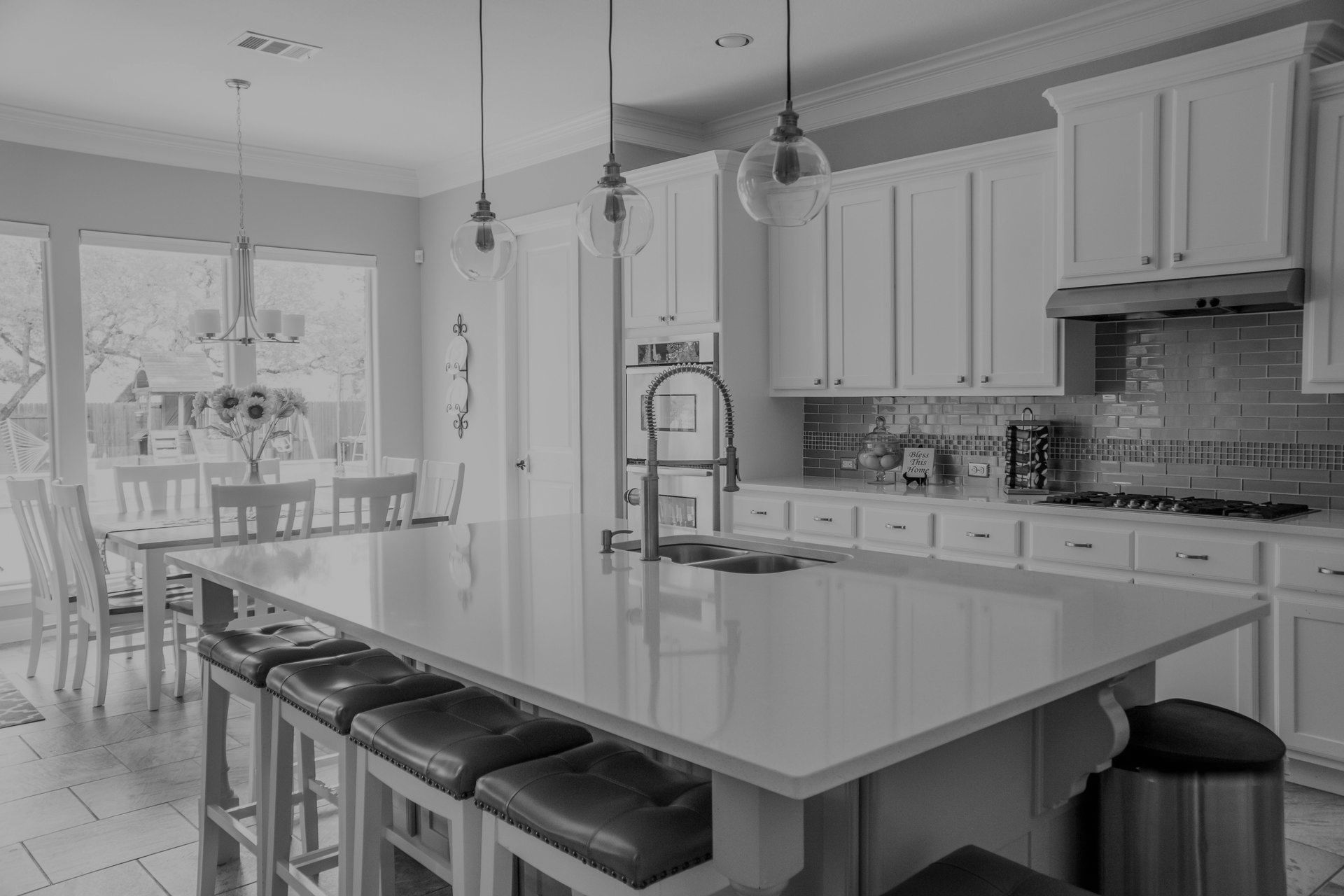 A black and white photo of a kitchen with white cabinets and a large island.
