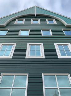 Looking up at a green building with lots of windows.