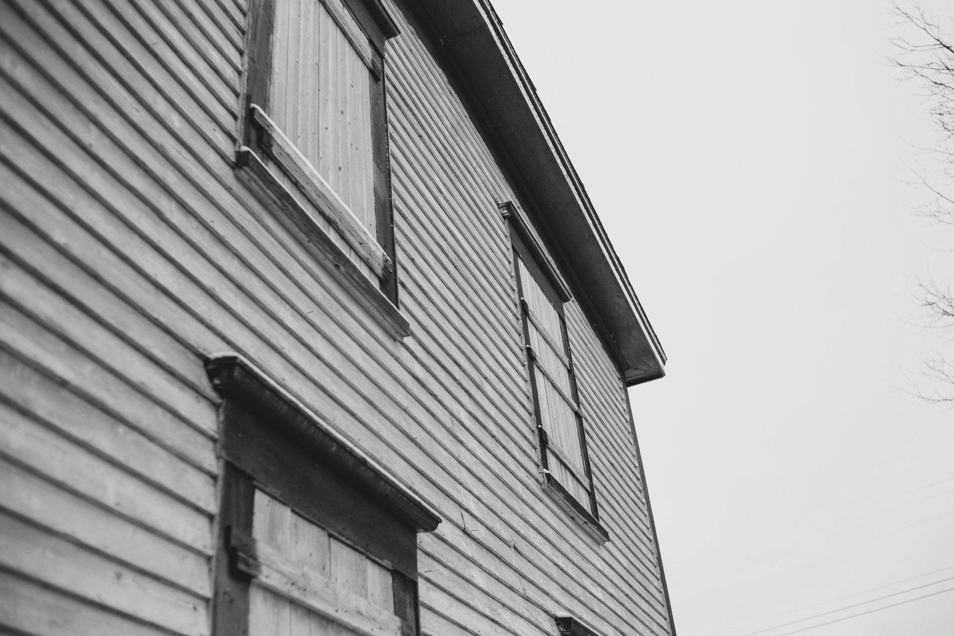 A black and white photo of a house with shutters on the windows.