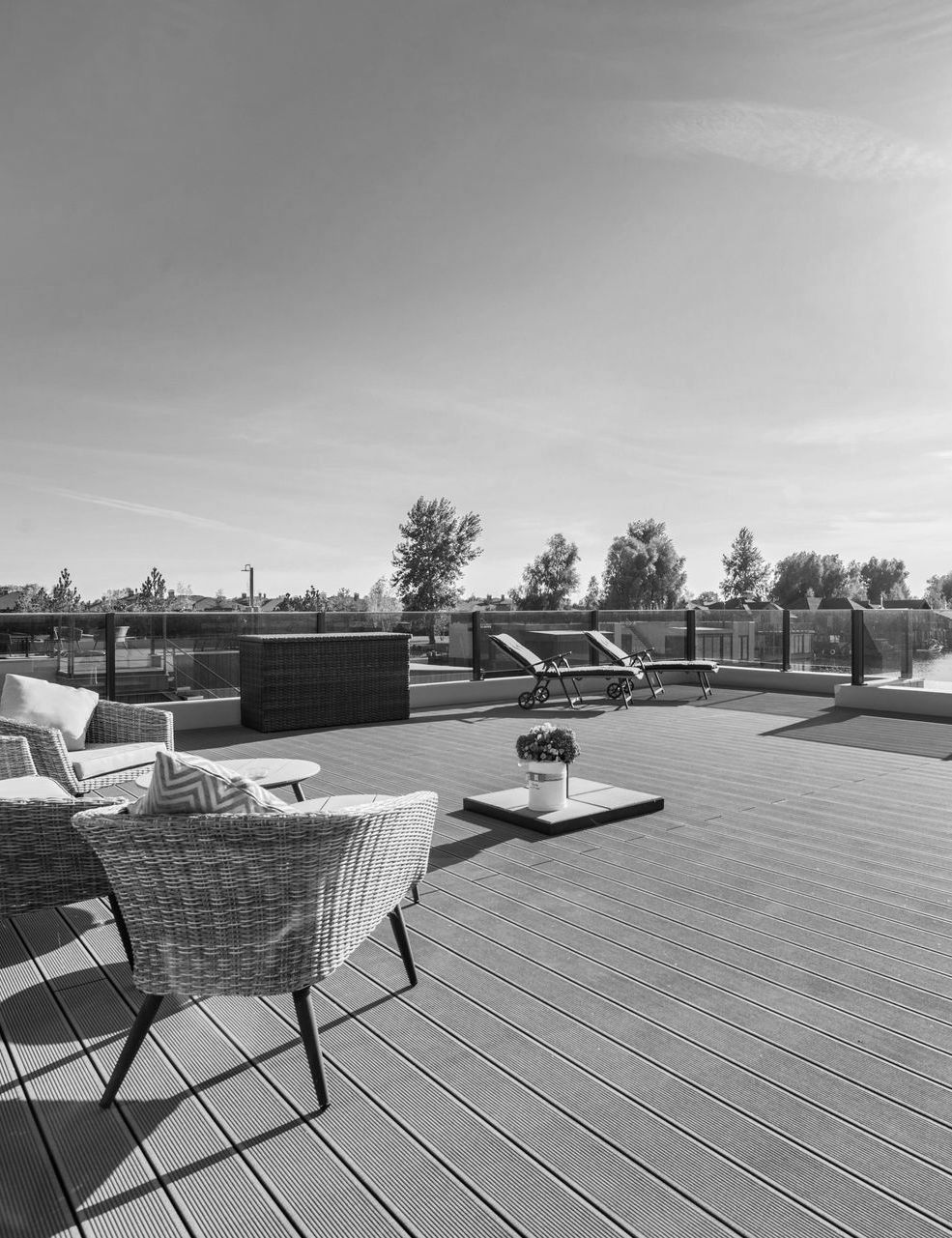 A black and white photo of a patio with chairs and a table.