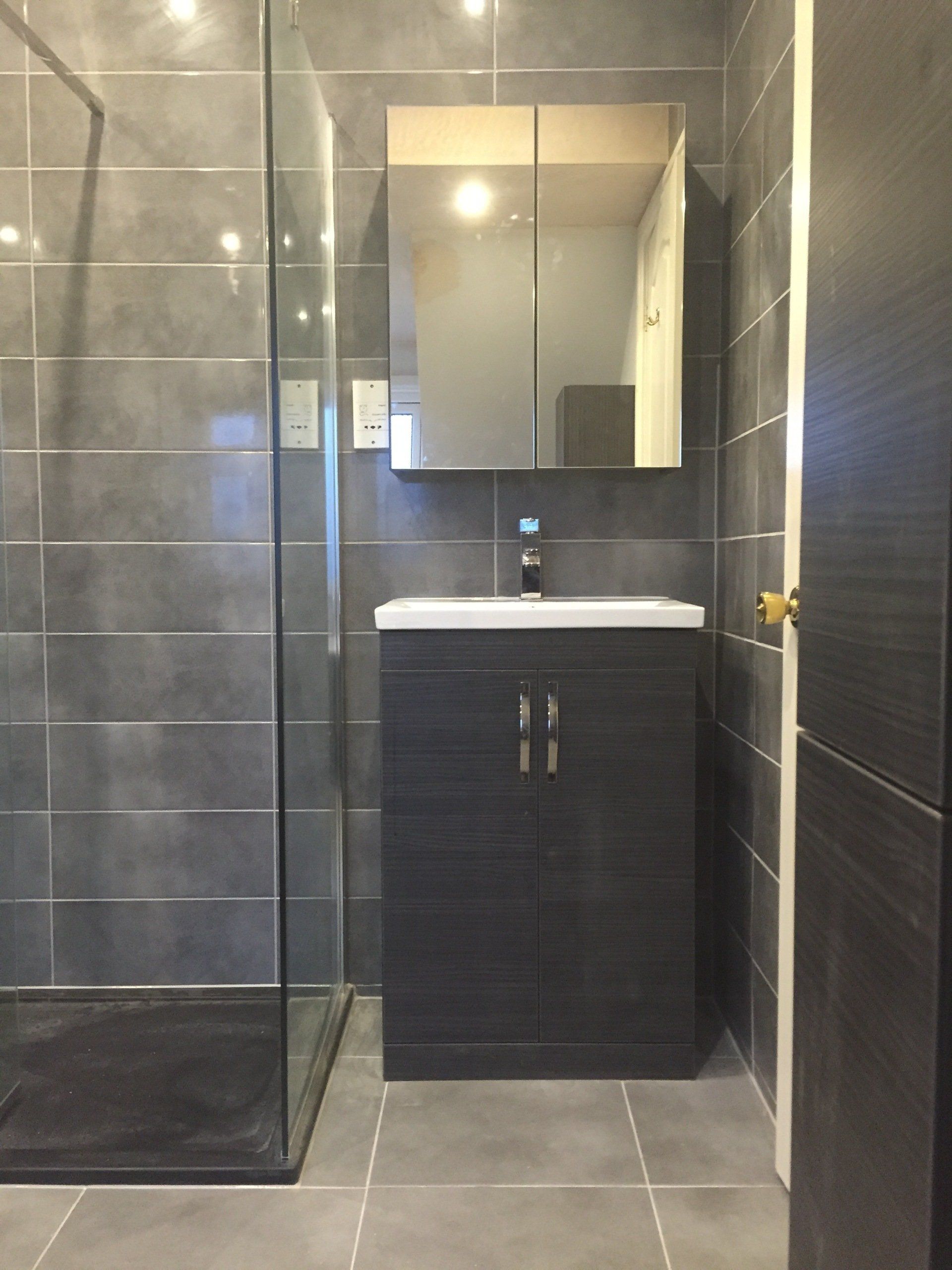 Gray tiled bathroom with shower, vanity, and mirror.