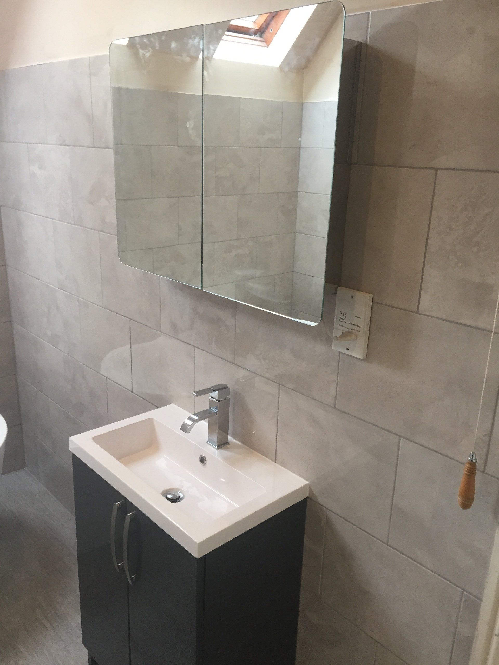Bathroom with a vanity, sink, mirror, and tiled walls.